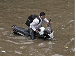 Một người Ấn Độ ì ạch lái chiếc xe máy ngập quá nửa trong nước