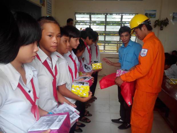 Nhân viên công ty Điện lực Kiên Giang tặng quà lồng ghép tuyên truyền tiết kiệm điện cho học sinh