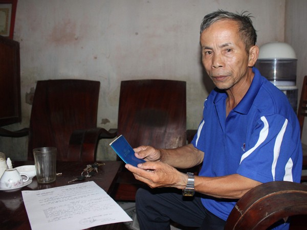 Ông Hoàng Văn San cầm cuốn sổ Trợ cấp mất sức lao động trước đây của mình