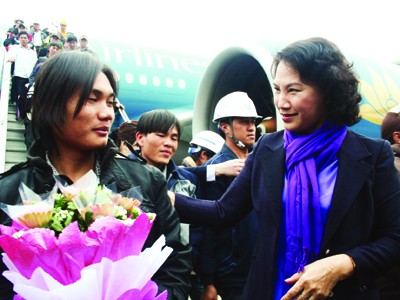 Bộ trưởng Nguyễn Thị Kim Ngân tặng hoa cho lao động sau khi xuống máy bay, sáng qua Ảnh: Đình Thắng
