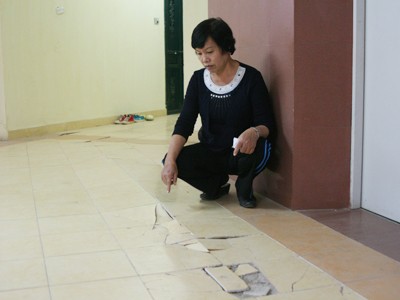 Bà Nguyễn Thị Kim, tổ phó tổ dân phố nhà B3B, ngồi trước nền nhà bị bong tróc
