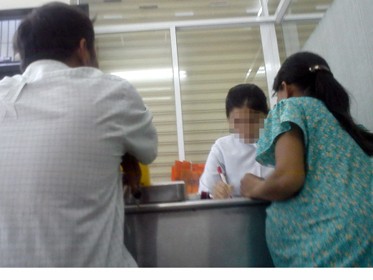 Ông H. (trái) dẫn người phụ nữ mang bầu đi làm thủ tục xét nghiệm máu tại phòng chẩn đoán y khoa trên đường Nguyễn Chí Thanh, Q.11 (ảnh chụp ngày 7-10-2010) Ảnh: N.K. (Tuổi Trẻ)