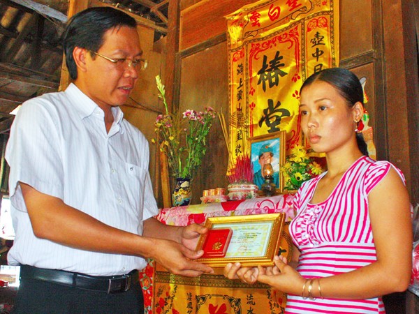 Anh Phan Văn Mãi trao huy hiệu “Tuổi trẻ dũng cảm” (của T.Ư Đoàn truy tặng đoàn viên Huỳnh Văn Tùng) cho vợ anh Tùng