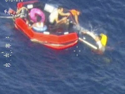 Những người tị nạn đang cố trèo lên một chiếc xuồng cứu hộ. (Ảnh: AP)