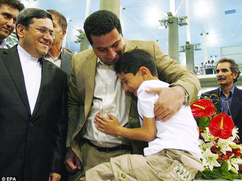 Nhà khoa học Shahram Amiri ôm cậu con trai 7 tuổi sau khi trở về Tehran. Ảnh: EPA
