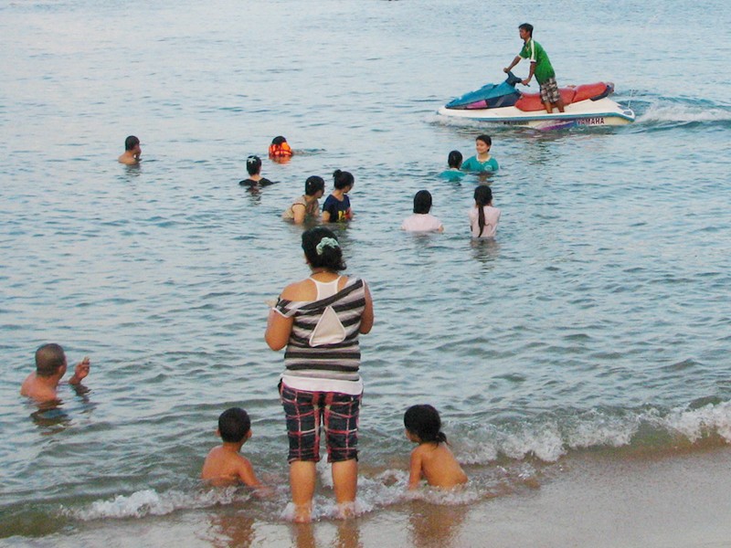 Một chiếc mô tô nước chạy sát phụ nữ và trẻ em đang tắm biển, ảnh chụp chiều 28-5.