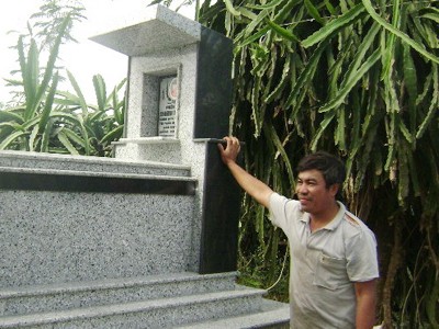 Anh Châu Văn Đông đứng bên mộ vợ, chị Đinh Thị Lan đã chết do bị điện giật ở vườn thanh long Ảnh: Châu Thành