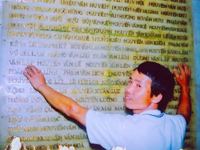 Anh Hoàng Văn Đạt chỉ vào tên ông Nguyễn Văn Lập tại Bảng vàng liệt sĩ Nghĩa trang đồi A1