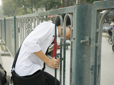 Rất nhiều người, đặc biệt là học sinh, sinh viên chui qua lỗ thủng của hàng rào sắt trên đường Nguyễn Trãi