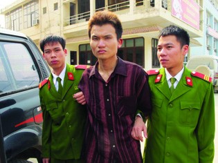 Đối tượng Đỗ Văn Nhuận (giữa) bị dẫn giải ra xe cảnh sát