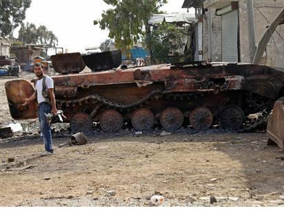 Một binh sỹ quân chính phủ đứng trước chiếc xe tăng đã hỏng tại Aleppo hôm 1-10.