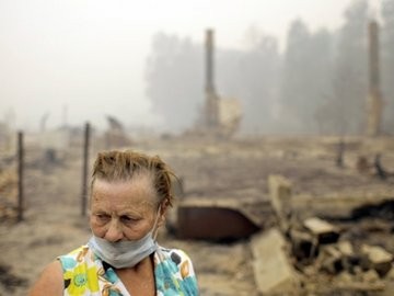 Người phụ nữ Nga này đứng trên nền ngôi nhà của mình vừa bị lửa rừng thiêu trụi. Ảnh: AP