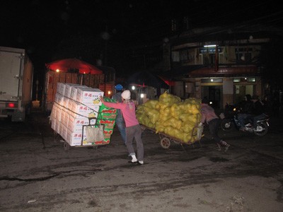 Hùng (phía trước) dọn hàng thuê trong đêm lạnh ở chợ đêm sinh viên