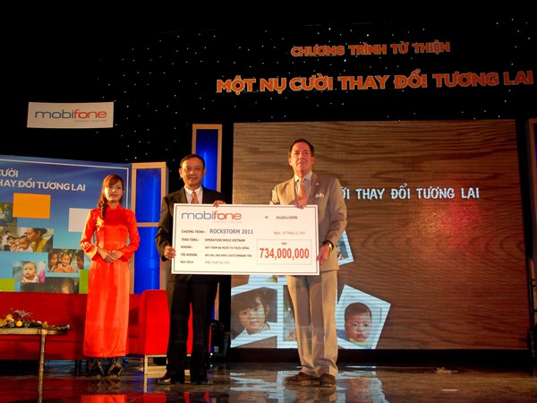 Ông Mai Văn Bình, Tổng Giám đốc MobiFone, trao 734 triệu đồng tiền bán vé Rockstorm cho ông Grey McFall, Phó Chủ tịch ban cố vấn Operation Smile Việt Nam