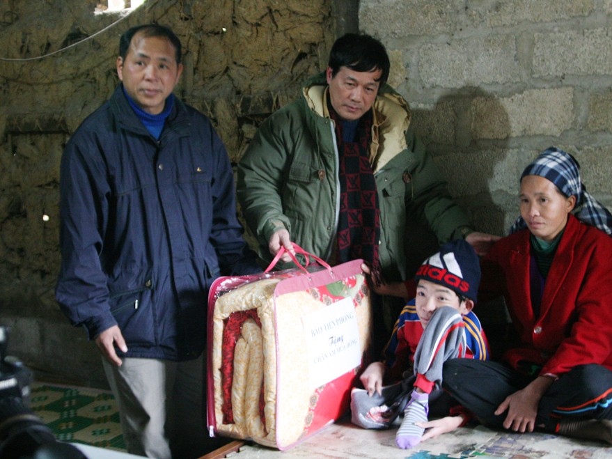 Đại diện báo Tiền Phong và chủ tịch xã Tự Do trao chăn ấm cho cháu Nông Văn Cù bị tàn tật