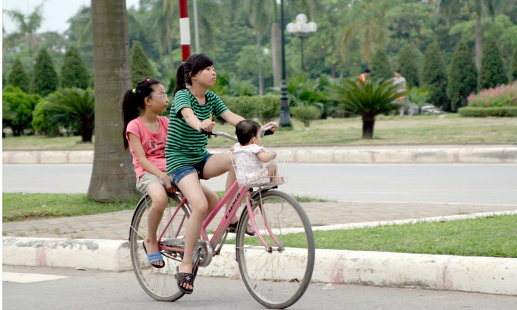Cho trẻ em vào giỏ xe dạo chơi trên đường Lê Đức Thọ (Từ Liêm).