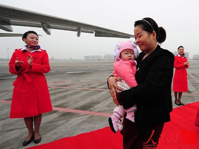 Cô Lou Wei bế con lên máy bay tham dự Đại hội Đảng Cộng sản Trung Quốc lần thứ 18 ở Bắc Kinh