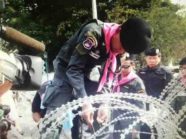 Một cảnh sát cắt dỡ hàng rào dây thép gai, mở đường cho người biểu tình vào trụ sở Cục Cảnh sát Thủ đô