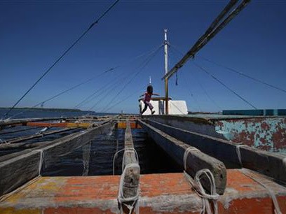 Một em bé nô đùa trên một chiếc tàu cá bị bỏ rơi trên bờ biển Philippines