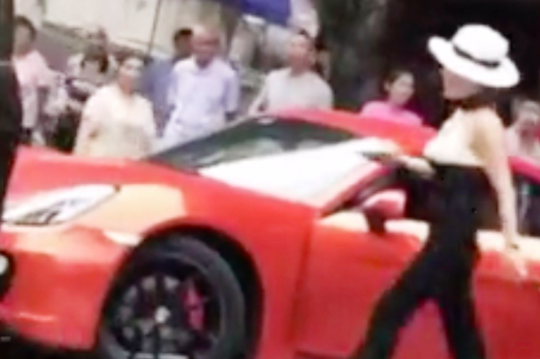 Người phụ nữ đội mũ lái chiếc xe màu đỏ bị ghi hình hành động sỉ nhục và tấn công người đi xe phía sau