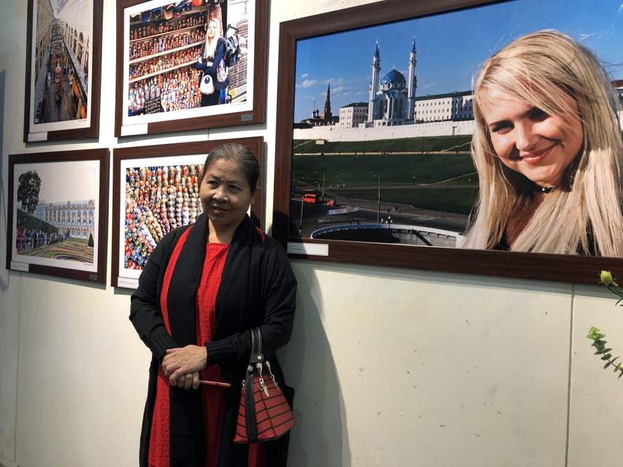 Một người xem triển lãm chụp ảnh lưu niệm bên bức ảnh cô gái Nga. (Ảnh: Thu Loan