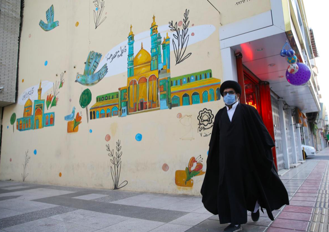 Một giáo sĩ Iran ở TP Qom đeo khẩu trang hôm 24/3. (Ảnh: Reuters)