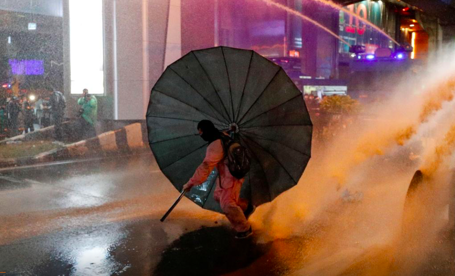 Một người biểu tình dùng ô chống lại vòi rồng của cảnh sát. (Ảnh: Reuters)