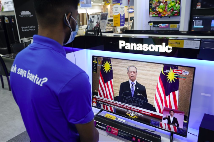Nhân viên một cửa hàng điện tử ở Kuala Lumpur xem Thủ tướng Muhyiddin phát biểu trên truyền hình ngày 12/1. (Ảnh: AP)