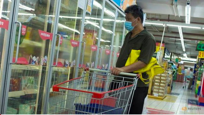 Một người đàn ông nhìn tủ chứa thực phẩm đông lạnh trong siêu thị ở Bắc Kinh. (Ảnh: Reuters)