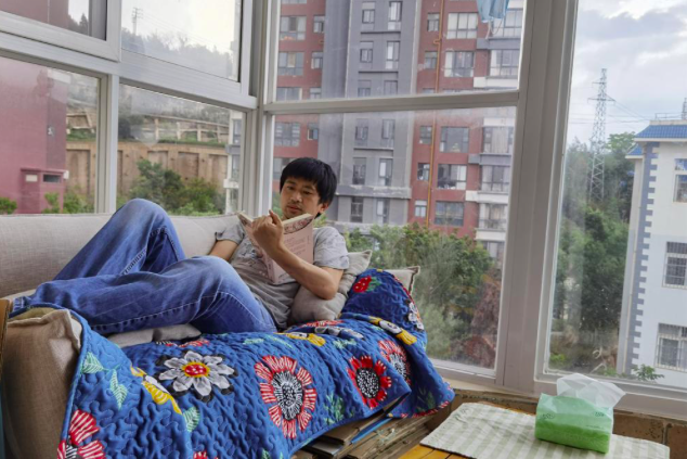 Guo Jianlong thảnh thơi nằm đọc sách trong căn hộ của anh ở tỉnh Vân Nam. (Ảnh: AP)