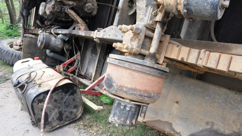 Xe tải chở gỗ tràm rơi lốp lật nhào bên đường.