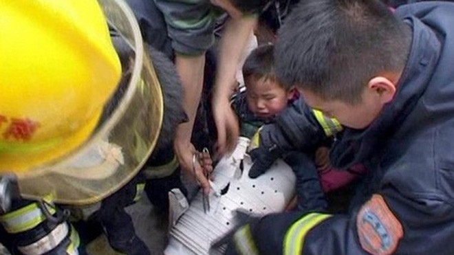 Các nhân viên cứu hộ đang giải cứu bé Tao Peng ra khỏi lồng máy giặt.