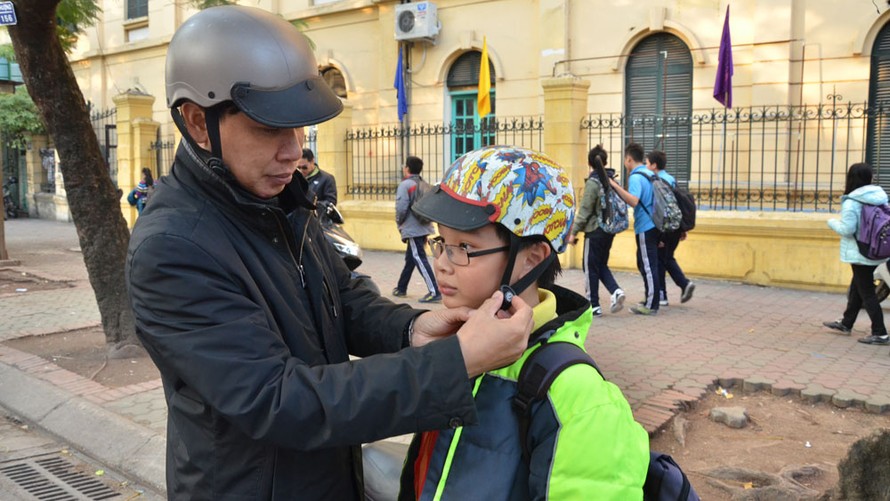 Trẻ em từ 6 tuổi trở lên khi ngồi trên xe gắn máy bắt buộc đội mũ bảo hiểm cài quai đúng quy cách. Ảnh: Thanh Hà.