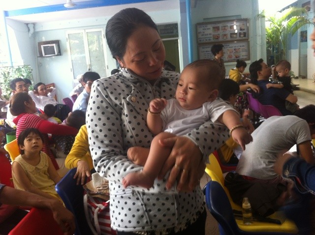 Bé Nguyễn Quốc Huy trong vòng tay dì ruột đến tái khám tại Bệnh viện Nhi đồng 1. Ảnh: Quốc Ngọc.