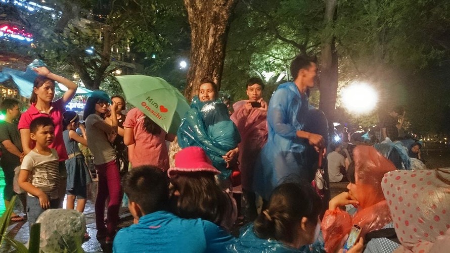 Nhiều người mặc áo mưa chờ xem pháo hoa tối 30/4 tại Hồ Gươm.