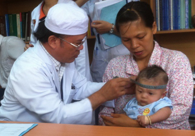 Bác sĩ Nguyễn Quang Vinh đang khám thần kinh cho bé Phát. Ảnh: Quốc Ngọc.