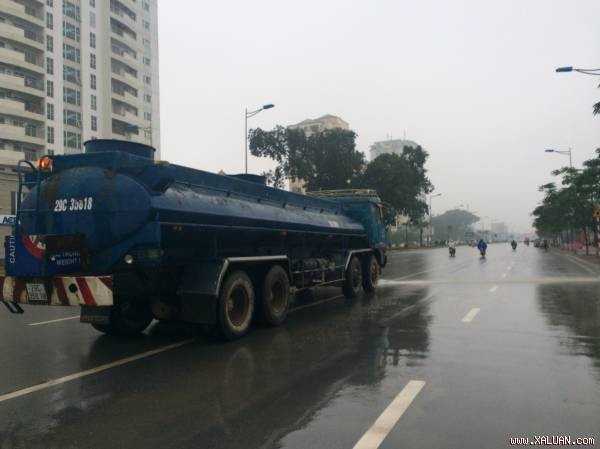 Nhiều người đi đường tỏ ra bất ngờ khi chứng kiến hình ảnh xe bồn chở nước rửa đường giữa trời mưa.