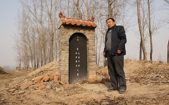Ông Li Fucai đứng cạnh ngôi mộ từng chôn cất thi thể cha và mẹ ông. Ảnh: The Telegraph 