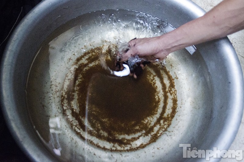 Nước chứa đầy cặn bẩn màu nâu sau tại một hộ gia đình trong thôn Tựu Liệt.