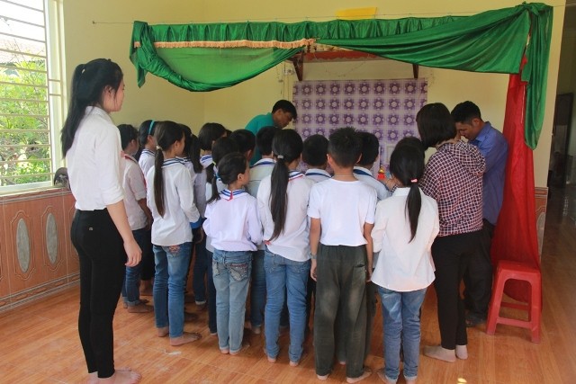 Cô và các bạn trong lớp 4C, trường Tiểu học Diễn Quảng đưa giấy khen và phần thưởng đến cho em Trần Việt Hưng.