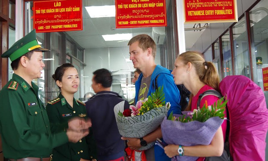 Đại diện Đồn Biên phòng Cửa khẩu Quốc tế Lao Bảo tặng hoa cho hai vị khách quốc tế đầu tiên nhập cảnh bằng thị thực điện tử qua đường bộ. 