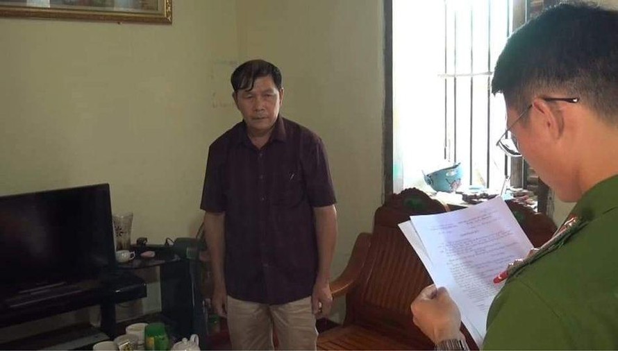 Ông Dương (bìa trái) nghe đọc quyết định khởi tố, bắt tạm giam để điều tra hành vi ăn chặn tiền của người nghèo -Ảnh: CB