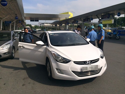 Thanh tra Sở GTVT lập biên bản taxi Uber tại nhà ga quốc nội sân bay Tân Sơn Nhất sáng 5.12 - Ảnh: Đình Mười