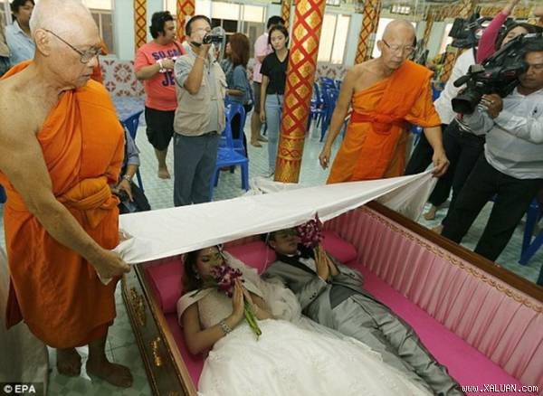 Một cặp đôi nằm trong quan tài thực hiện nghi lễ. Các nhà sư phủ vải trắng lên họ. (Nguồn: Daily Mail)