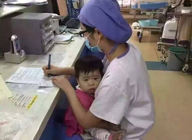 Hình ảnh nữ y tá ôm bé gái mồ côi khi làm việc. (Nguồn: CCTV News) 