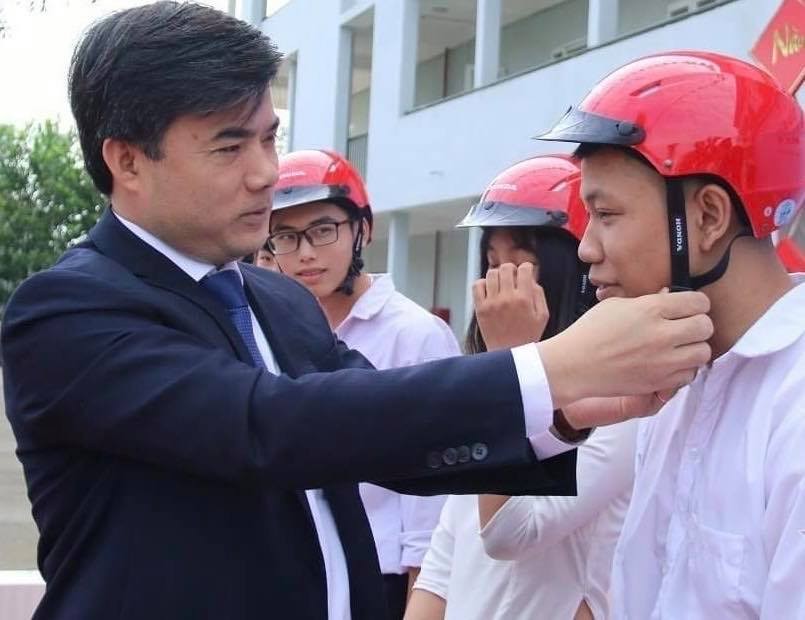 Ông Bùi Văn Linh tặng mũ bảo hiểm cho học sinh.