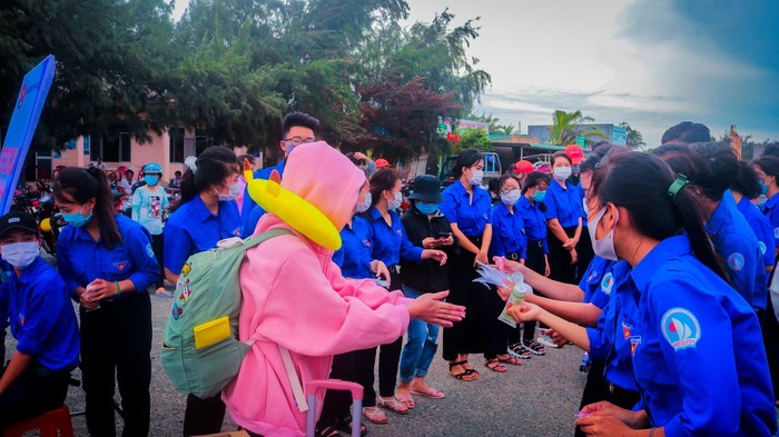 Học sinh đảo Phú Quý vào đất liền, được tình nguyện viên phát nước rửa tay sát khuẩn. 