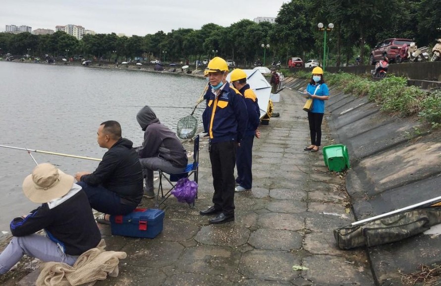 Câu cá trái phép trên hồ Định Công đang diễn ra công khai. Trong ảnh, nhân viên Cty Thoát nước ra nhắc nhở nhưng câu cá vẫn diễn ra.