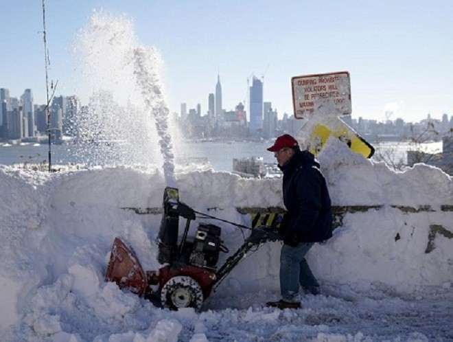 Một cư dân dùng máy xúc tuyết trước cửa nhà ở bang New Jersey. Ảnh: Reuters