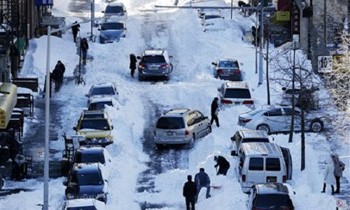 Người dân xúc tuyết phủ trên xe ở Henry Street, khu phố người Hoa, New York hôm 24/1. Ảnh: AP